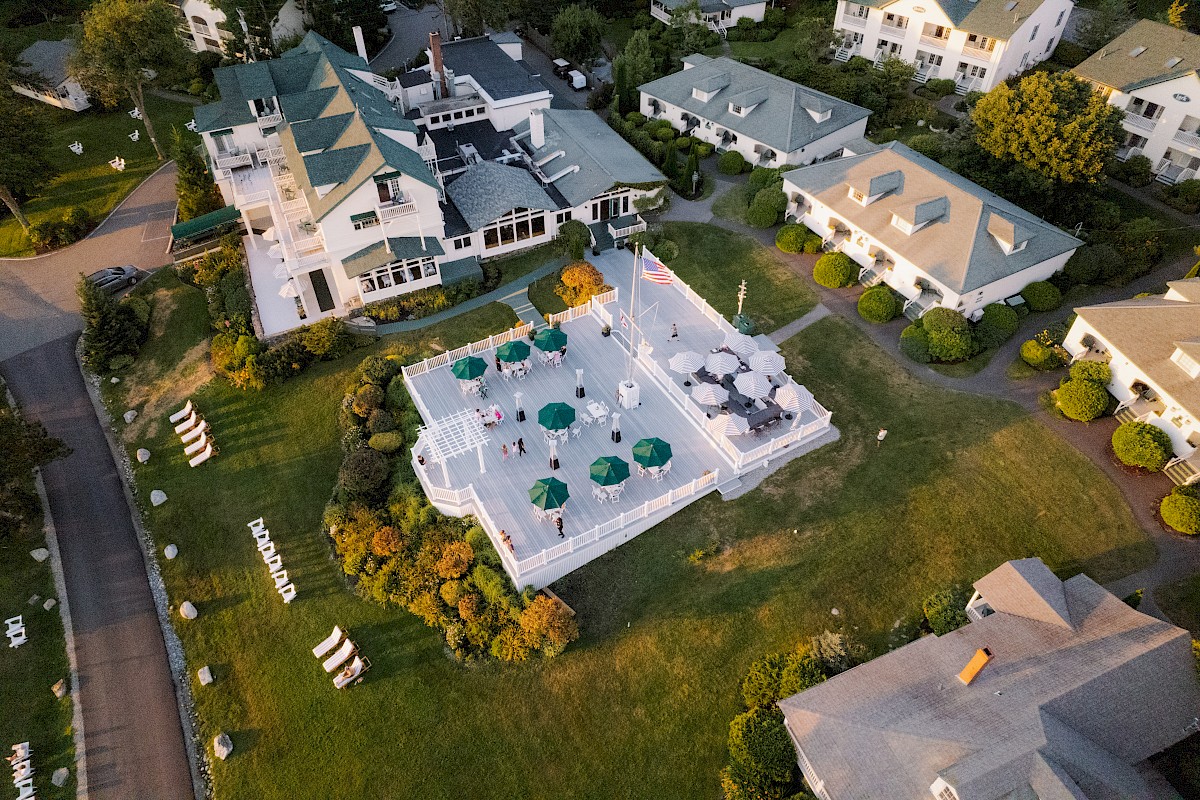 An aerial view of a community with multiple buildings, a central patio with umbrellas, and well-maintained green lawns ending the sentence.
