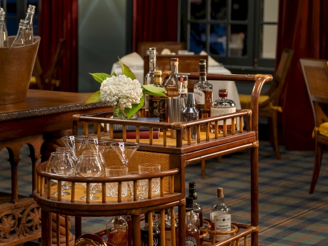 Elegant room with a bar cart stocked with glasses and bottles, next to cozy