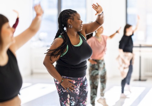 A group of people is participating in a lively dance or fitness class in a brightly lit room, enjoying the activity together.