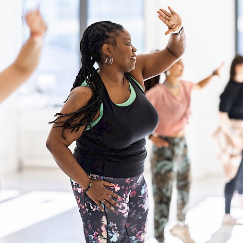 A group of people is participating in a lively dance or fitness class in a brightly lit room, enjoying the activity together.