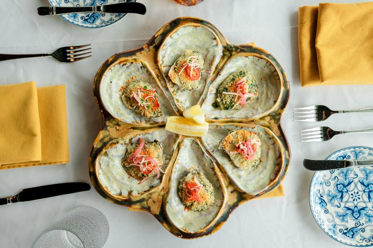 A flower-shaped serving dish with six compartments holds melty, herb-studded bites, surrounded by yellow napkins and blue-and-white tableware.